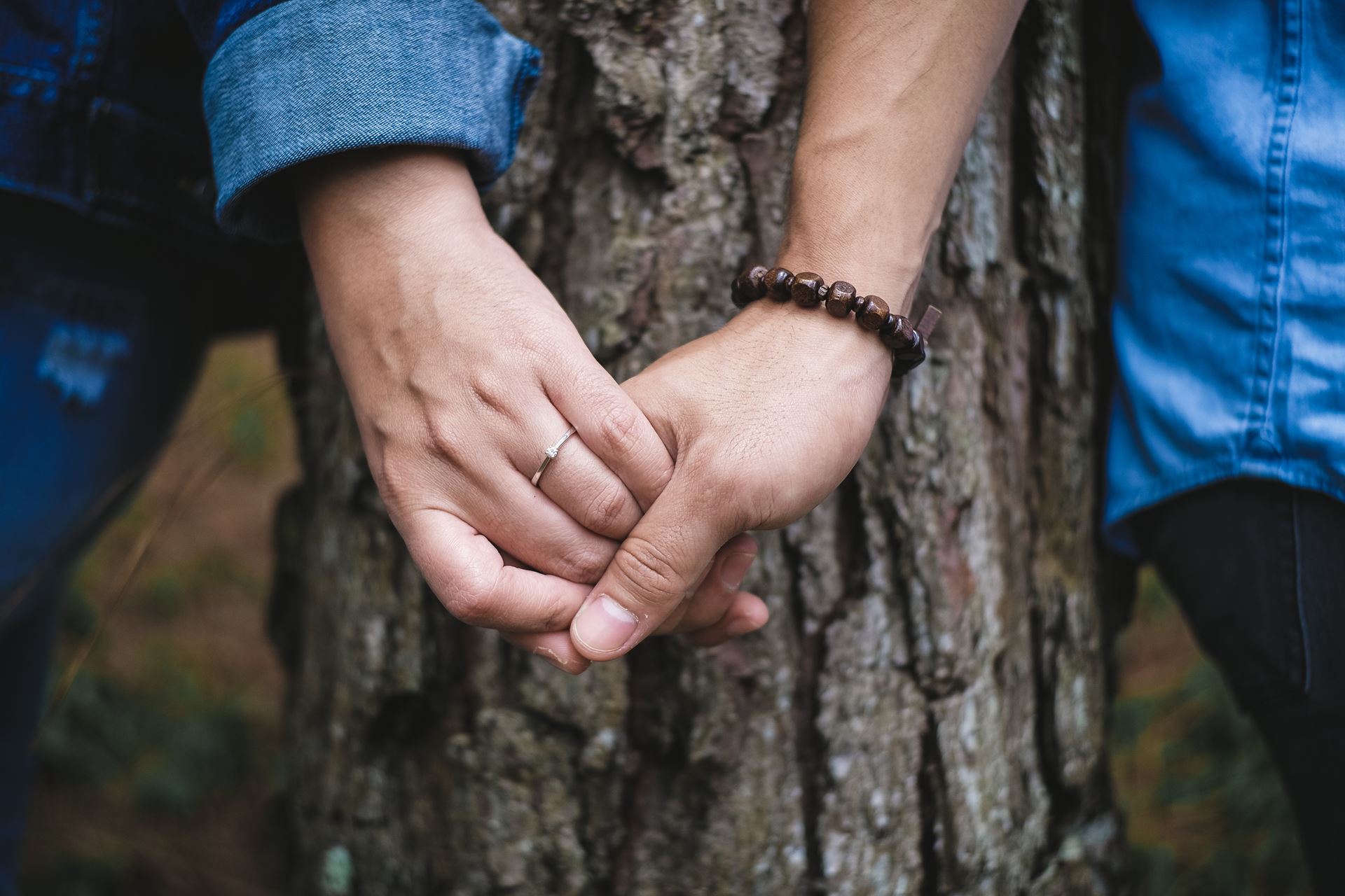 a close up of hands in front of a tree